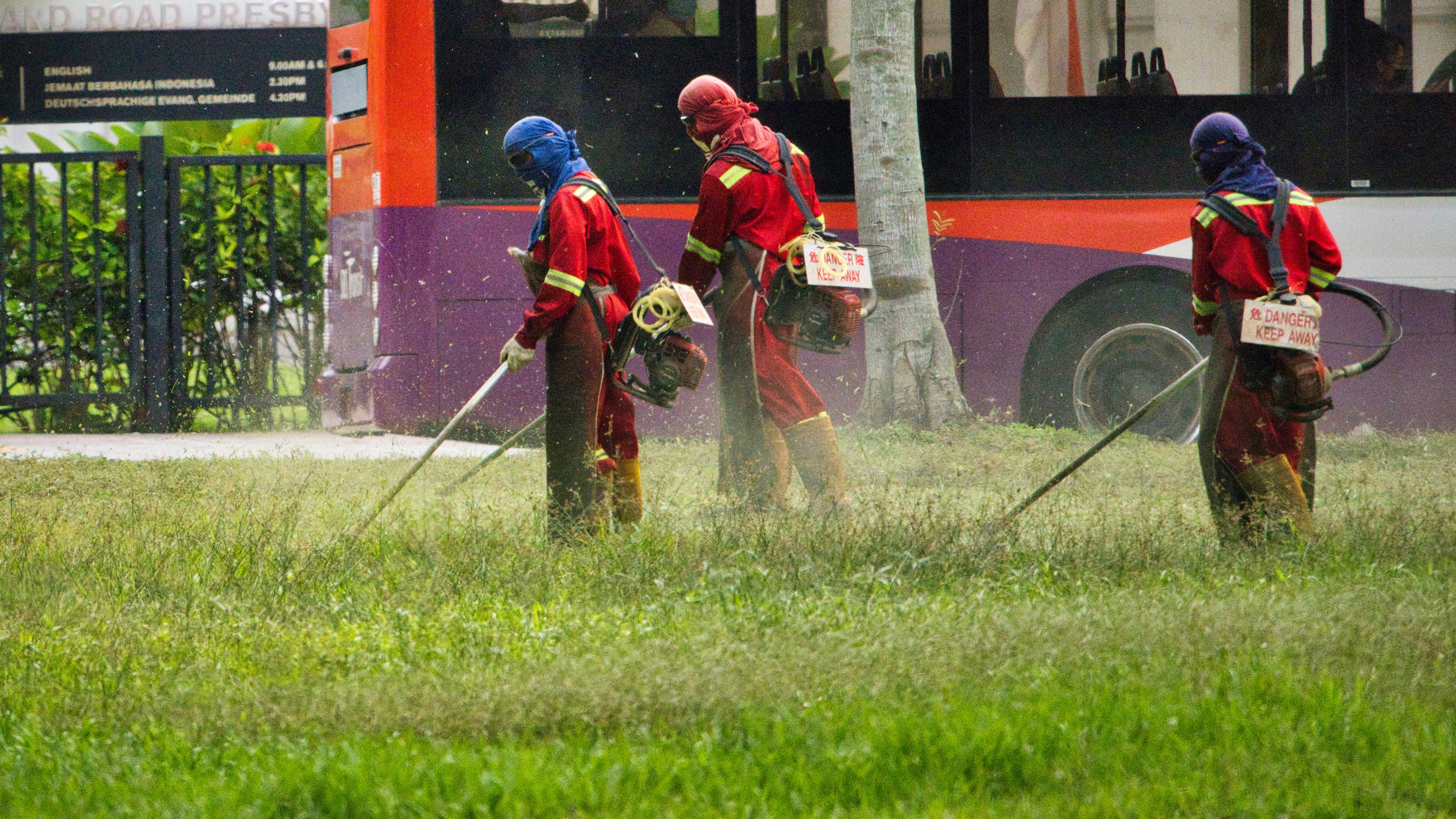 Workers in protective gear spraying chemicals on a lawn